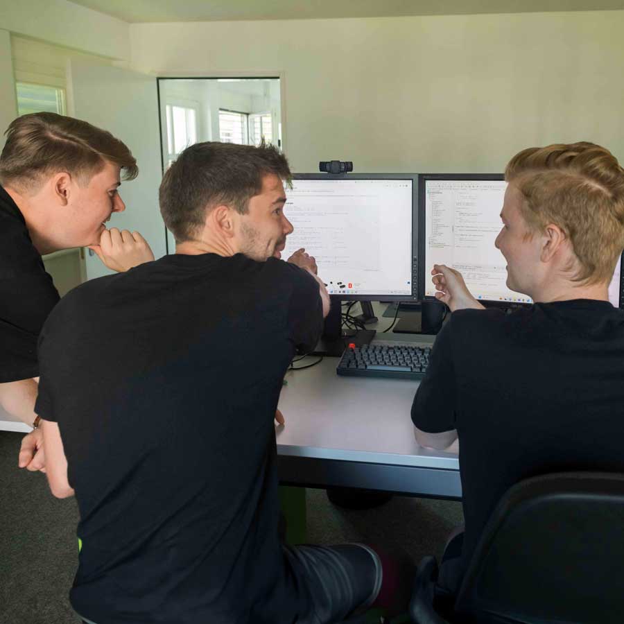 Three seated young men discussing in front of the screen