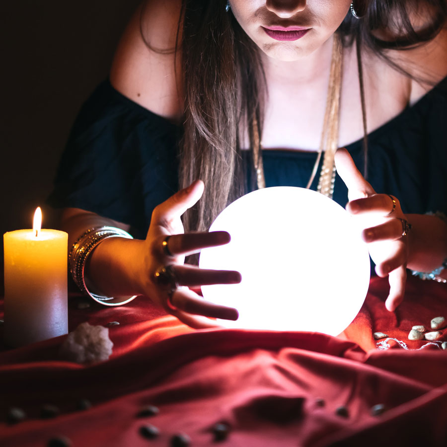 A fortune teller holds hands around a crystal ball